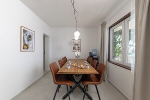 A dining area with a wooden table, brown chairs, and framed pictures on the walls.