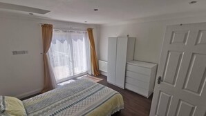A bedroom with a bed, a wardrobe, a radiator, and a door. - City Apartment Sleeps 4 with Garden (Romford)
