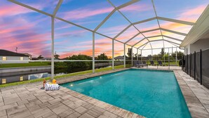 A covered swimming pool with a view of the sunset, a fire hydrant, and lounge chairs. - Sleeps 6, Pool, Bicycles, Waterfront: Whispering Sapphire (Cape Coral)
