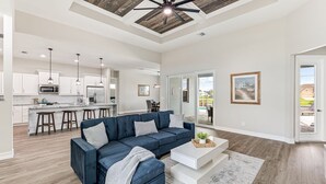 A spacious living room with a dark blue sofa, a white coffee table, and a wooden ceiling. - Sleeps 6, Pool, Bicycles, Waterfront: Whispering Sapphire (Cape Coral)