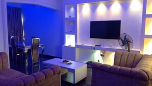 A modern living room with a flat-screen TV, a coffee table, and two sofas.