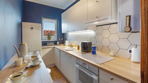 Una cocina moderna con armarios blancos, encimera de madera y ventana con vistas a un paisaje urbano.
