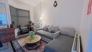 A modern living room with a grey sofa, a wooden coffee table, and a patterned rug. - MCRShared House-Big Bedroom Sleeps 3 (Manchester)