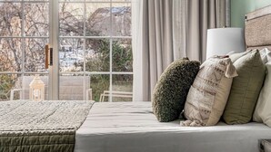 A bedroom with a large window, a bed with a quilt, and two decorative pillows. - Cozy Branson Studio Near Strip & SDC / Patio / Dog Friendly (Branson)