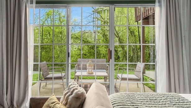 A room with a large sliding glass door leading to an outdoor patio with a table and chairs. - Cozy Branson Studio Near Strip & SDC / Patio / Dog Friendly (Branson)