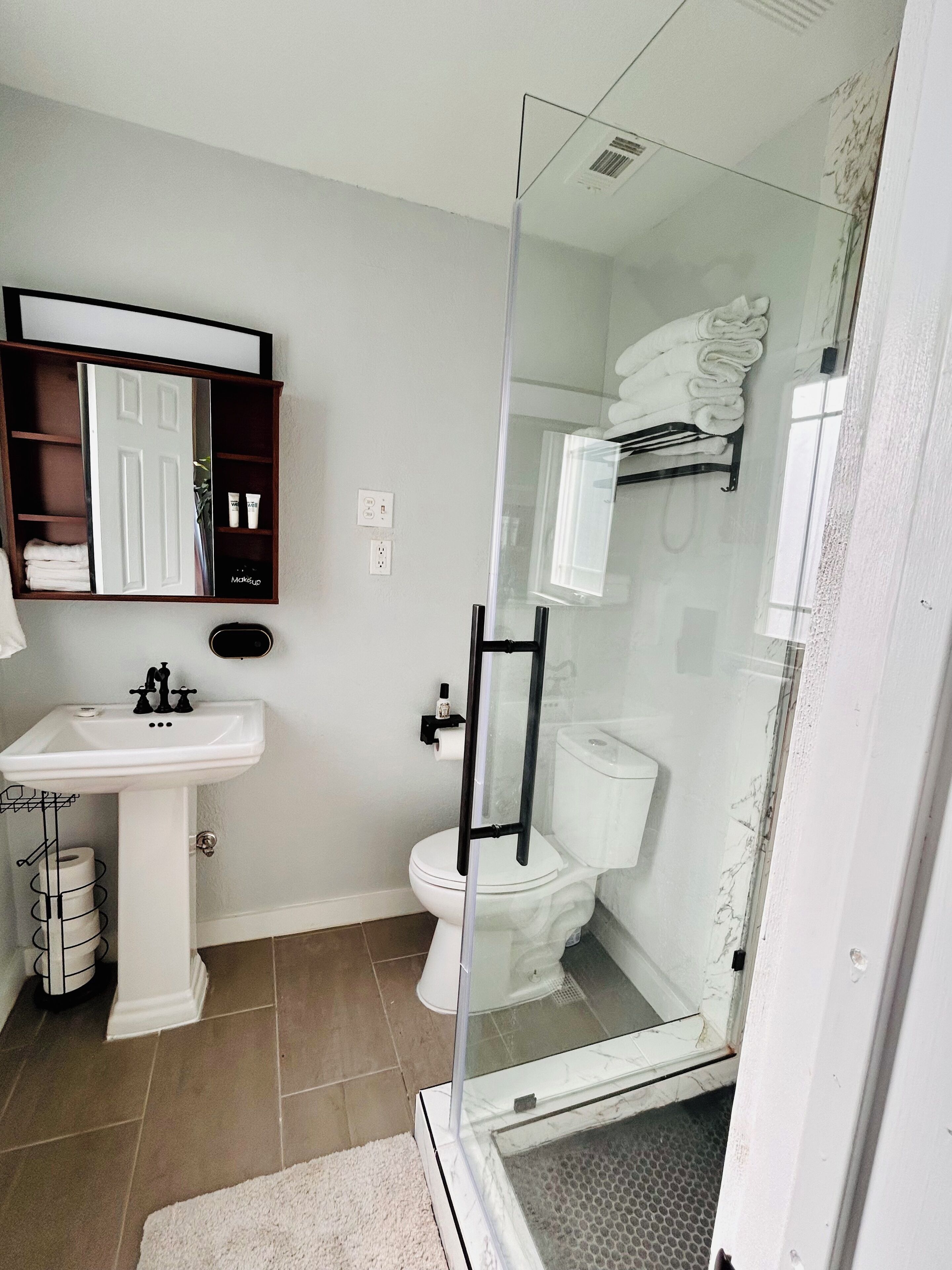 A bathroom with a white sink, toilet, and glass-enclosed shower.
