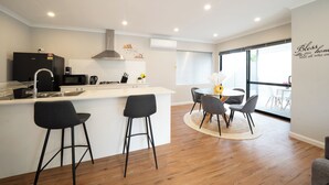A modern kitchen with a central island, bar stools, and a dining area with a round table and chairs.