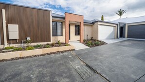 A modern residential building with a flat roof, a brick entrance, and a garage.