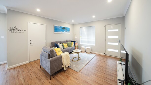 A modern living room with a grey sofa, a small round table, and a flat-screen TV.