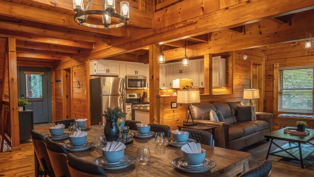 Un intérieur de cabane en bois spacieux, comprenant un coin repas, une cuisine et un espace salon.