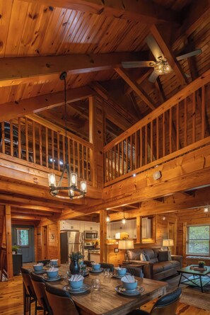 Un intérieur de cabane en bois spacieux, comprenant un coin repas, une cuisine et un espace salon.