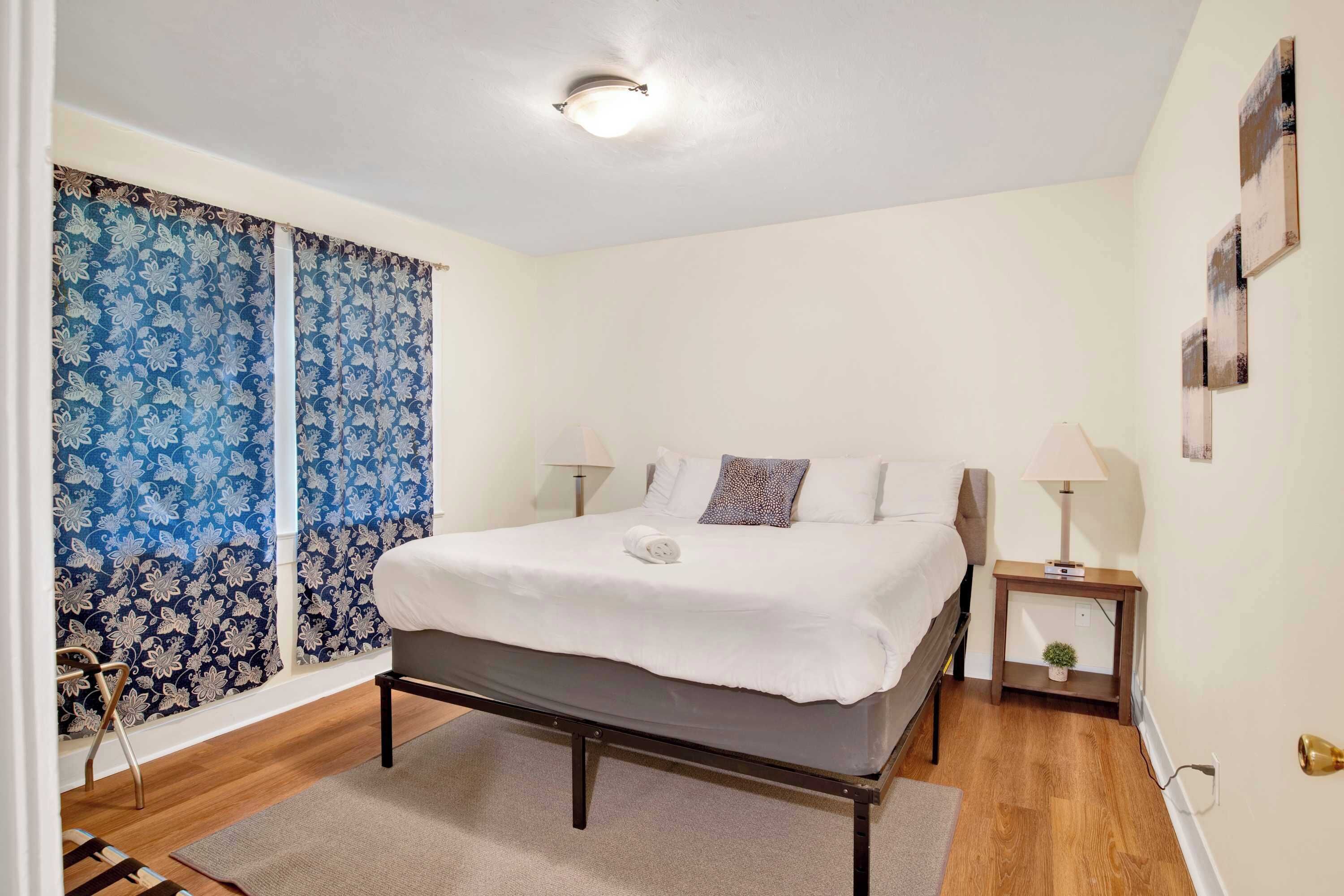 A neatly arranged bedroom with a bed, bedside tables, and curtains.