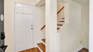 A clean, modern entryway with a white door, a staircase, and a wall-mounted security device. - Near Downtown and Cornerstone - Southern Sunshine (Mobile)
