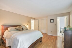 A bedroom with a wooden bed, a dresser, and a door leading to a bathroom. - 10 Mi to Crane Beach: Wooded Home Near Boston! (Topsfield)