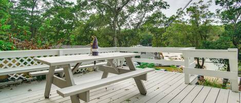 A wooden deck with picnic tables and a white railing.