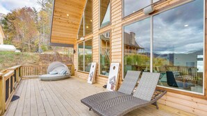 Eine Holzterrasse mit Liegestuhl und einer gepolsterten Sitzgruppe.