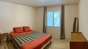 A bedroom with a bed, a nightstand, a window with curtains, and a mirror. - Beautiful renovated apartment in the countryside (CABANNES)