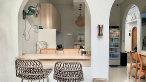 Cozinha com bancada de madeira, duas cadeiras de vime, luminária pendente e geladeira.