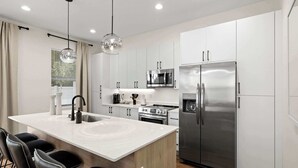 A modern kitchen with a central island, stainless steel appliances, and a pendant light.