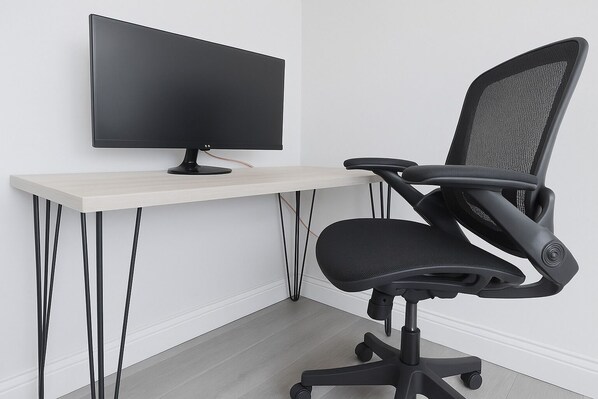 A modern office setup with a flat-screen monitor on a light wooden desk, a black office chair with mesh backrest, and a minimalist design. - Silicon Valley Airbnb (Sunnyvale)