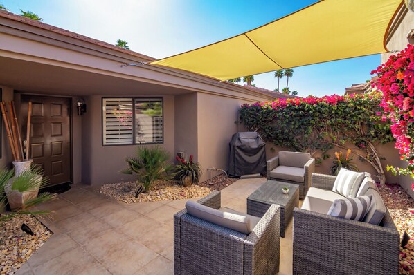 An outdoor patio with wicker furniture, a covered grill, and a yellow canopy. - 
The Country Club Experience in Palm Desert (Palm Desert)