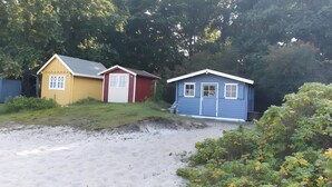 A beachside property with three small cabins, a sandy path, and dense greenery.