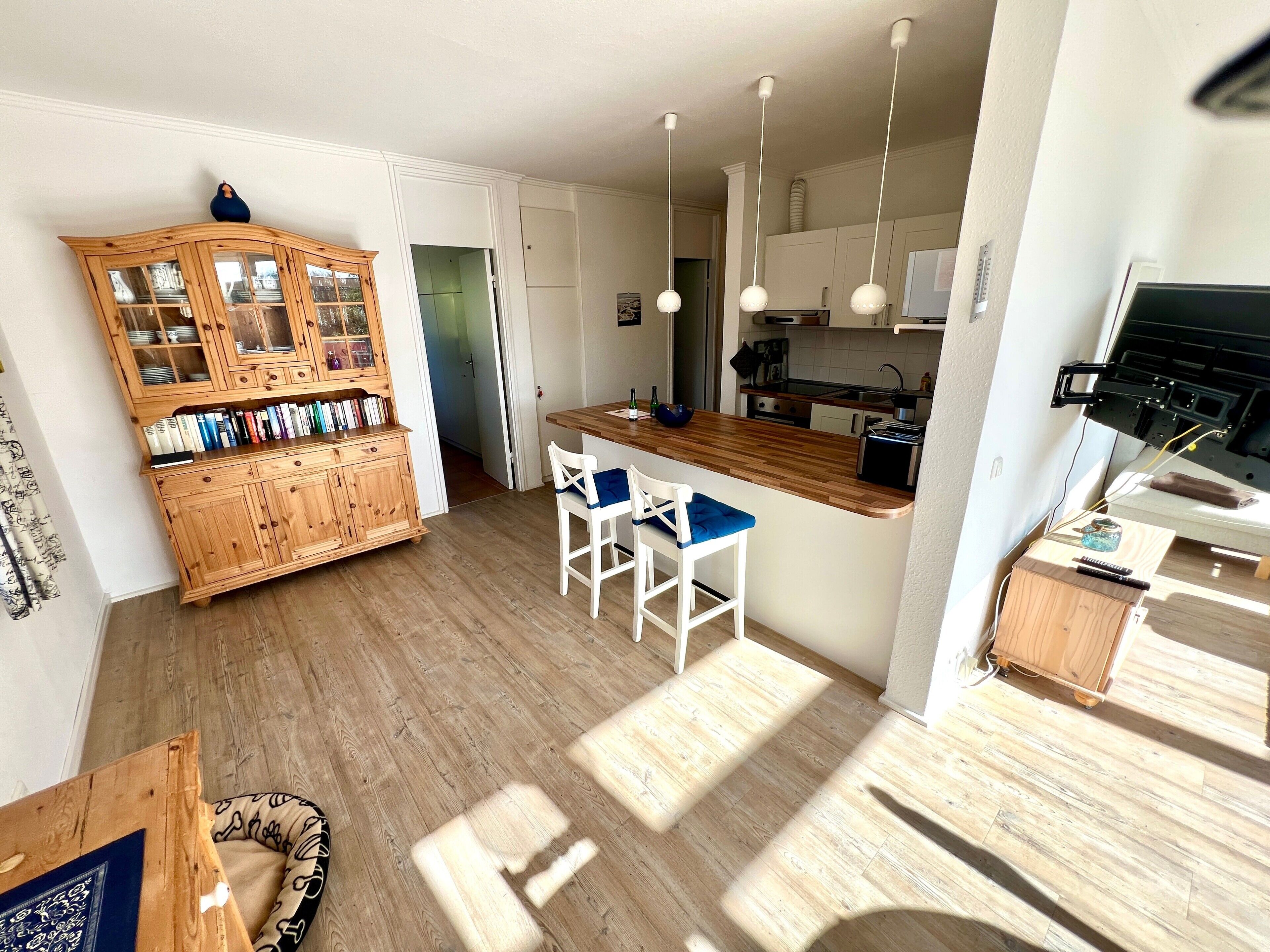 A modern kitchen with wooden cabinets, a central island, and pendant lighting.