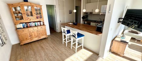 A modern kitchen with wooden cabinets, a central island, and pendant lighting.