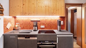 A modern kitchen with wooden cabinets, a built-in dishwasher, and a coffee maker. - Holiday Home 'Zaunkönig' with Mountain View and Private Terrace (Mittenwald)