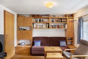 Una stanza accogliente con un divano, un tavolino, una libreria e una radio.