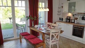 A kitchen with a dining table, chairs, a bench, and a view of the garden through the sliding glass door. - Apartment 'Ferienwohnung Baltic Sea' with Private Terrace, Private Garden and Wi-Fi (Börgerende-Rethwisch)