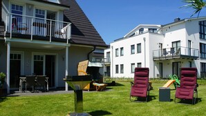 A residential building with a balcony, outdoor seating, and a grassy yard. - Apartment 'Ferienwohnung Baltic Sea' with Private Terrace, Private Garden and Wi-Fi (Börgerende-Rethwisch)