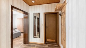 Un couloir avec un plancher en bois, un miroir, une porte et un lit dans la pièce adjacente.