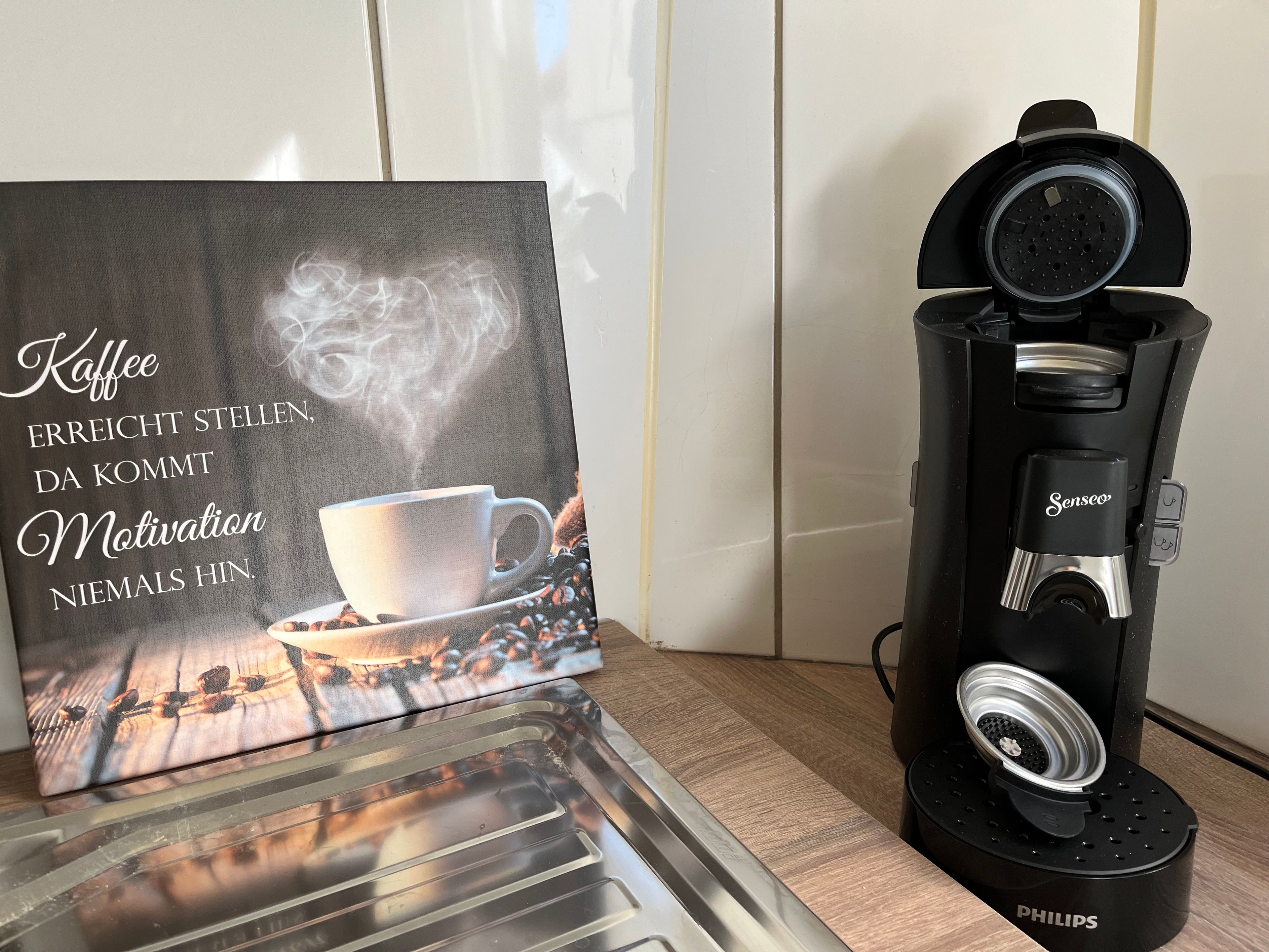 A coffee maker with a coffee cup and steam, and a motivational quote on a card.