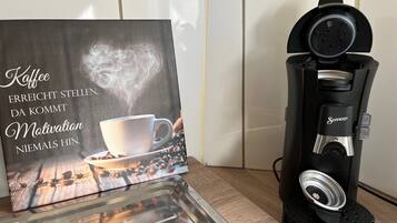A coffee maker with a coffee cup and steam, and a motivational quote on a card.