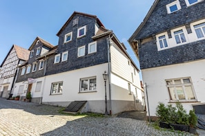 Un bâtiment européen traditionnel, doté d’un toit à forte pente, d’une façade blanche et bleu foncé, et situé sur une rue pavée.