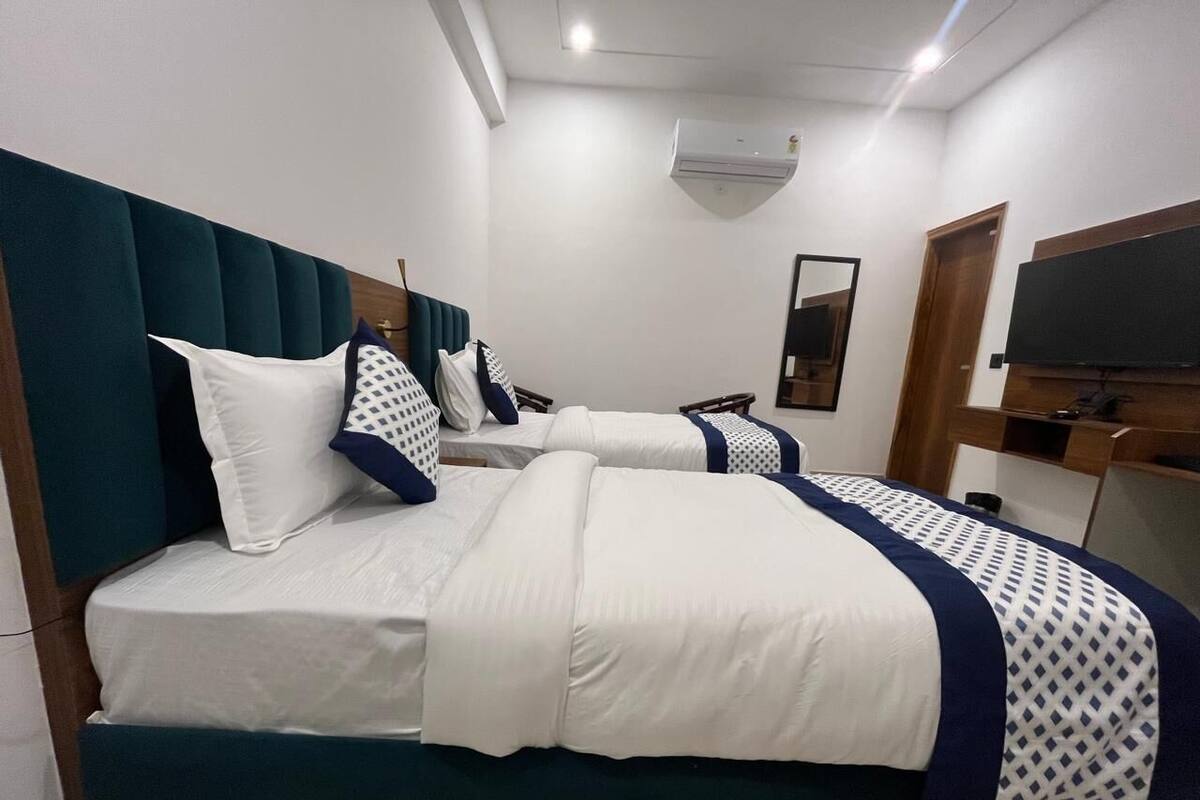 Ett hotellrum med två sängar, en platt-TV, en spegel och en luftkonditioneringsanläggning.