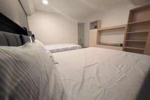 Une chambre avec deux lits, une armoire et un petit bureau.
