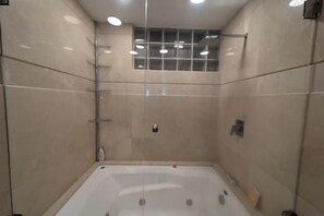 Une salle de bain moderne avec une douche à parois de verre, des murs carrelés et une baignoire.
