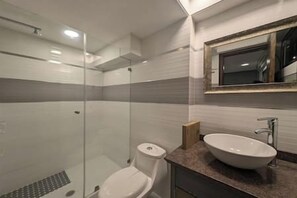 Une salle de bain avec une douche à parois de verre, des toilettes et un lavabo avec un miroir au-dessus.