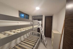 Un lit superposé dans un couloir, avec une porte et une fenêtre.