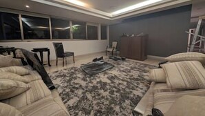 Ein modernes Wohnzimmer mit großem Fenster, einer Couch, einem Couchtisch und einem Schrank.