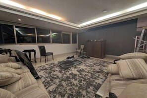 Un salon moderne avec une grande fenêtre, un canapé, une table basse et un meuble.