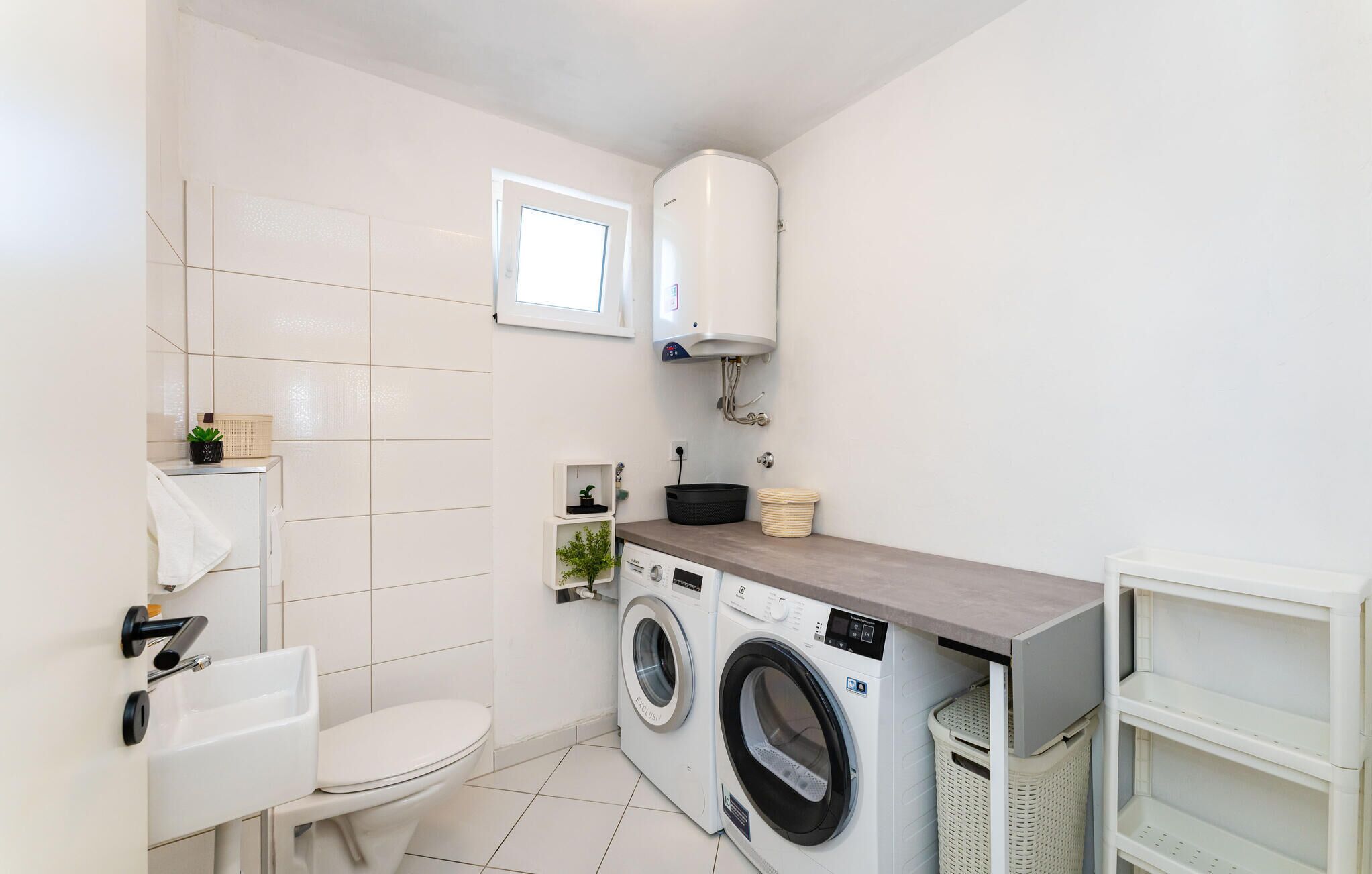 Un baño pequeño y moderno con inodoro, lavabo, lavadora y calentador de agua.