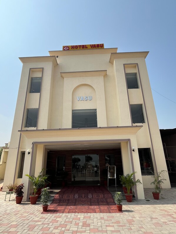 A two-story building with a sign reading "HOTEL VASU" and a large arched entrance.