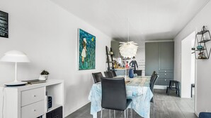 A modern dining area with a table set for four, a white console with drawers, a painting on the wall, and a kitchen in the background. - "Isabel" - 600m from the sea by Interhome (Blokhus)