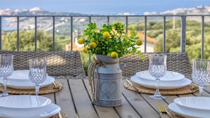 Mesa lista para comer con vista al mar, una planta en maceta y un jarrón decorativo.