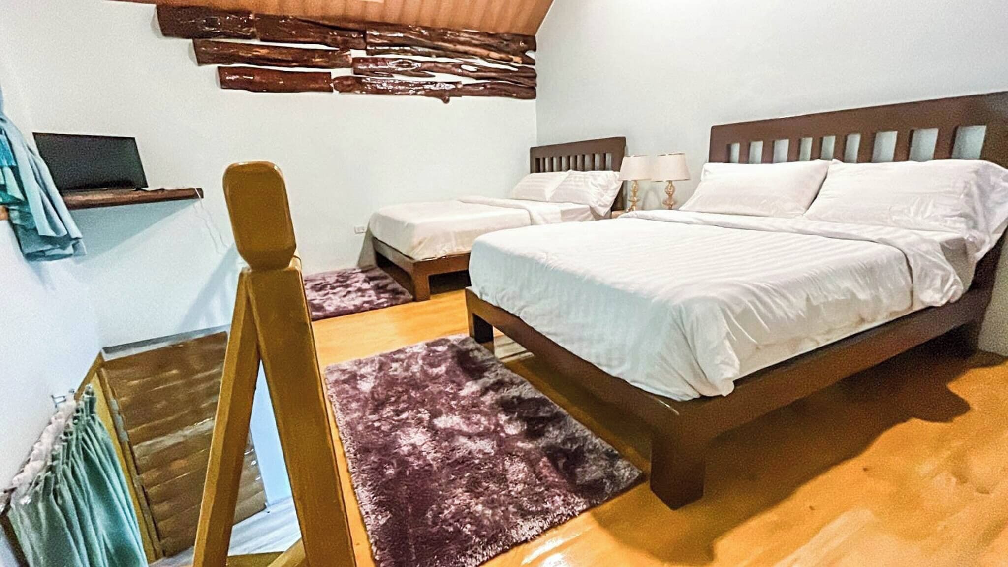 Une chambre à coucher avec un lit en bois, deux tables de chevet, une petite étagère et une fenêtre avec des stores.