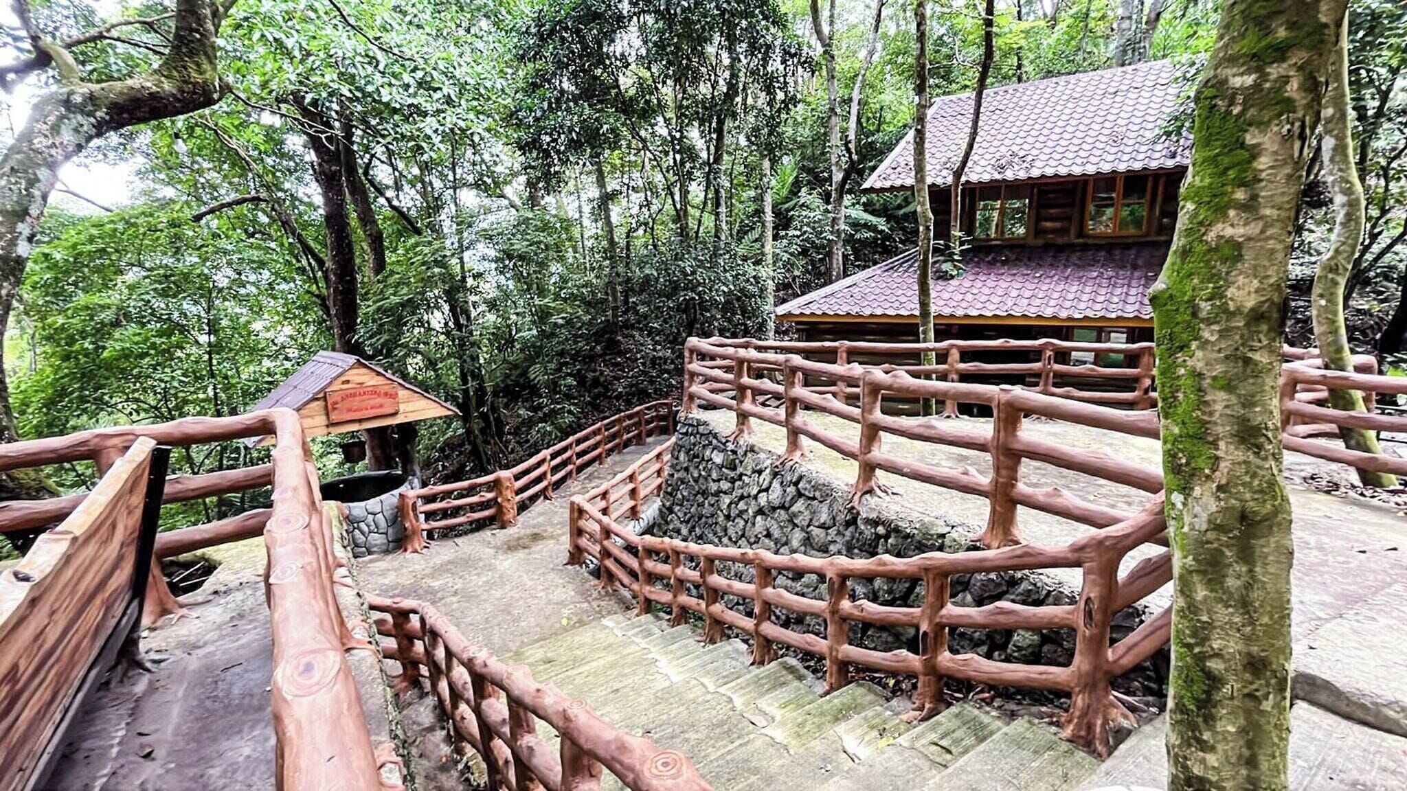 A wooden staircase with a stone wall and a wooden structure with a tiled roof.