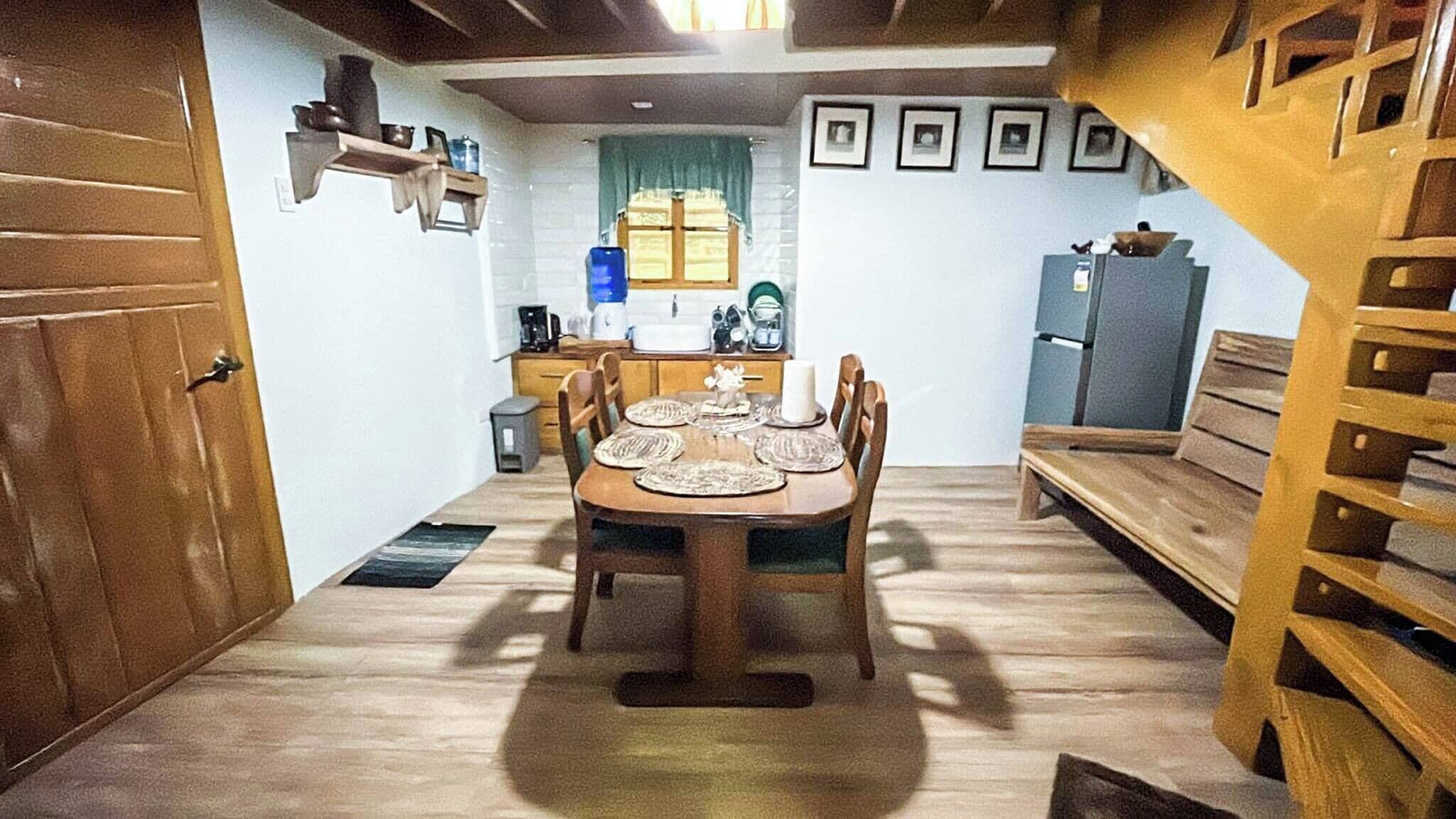 A compact kitchen with a dining table set for four, a sink, and a refrigerator.